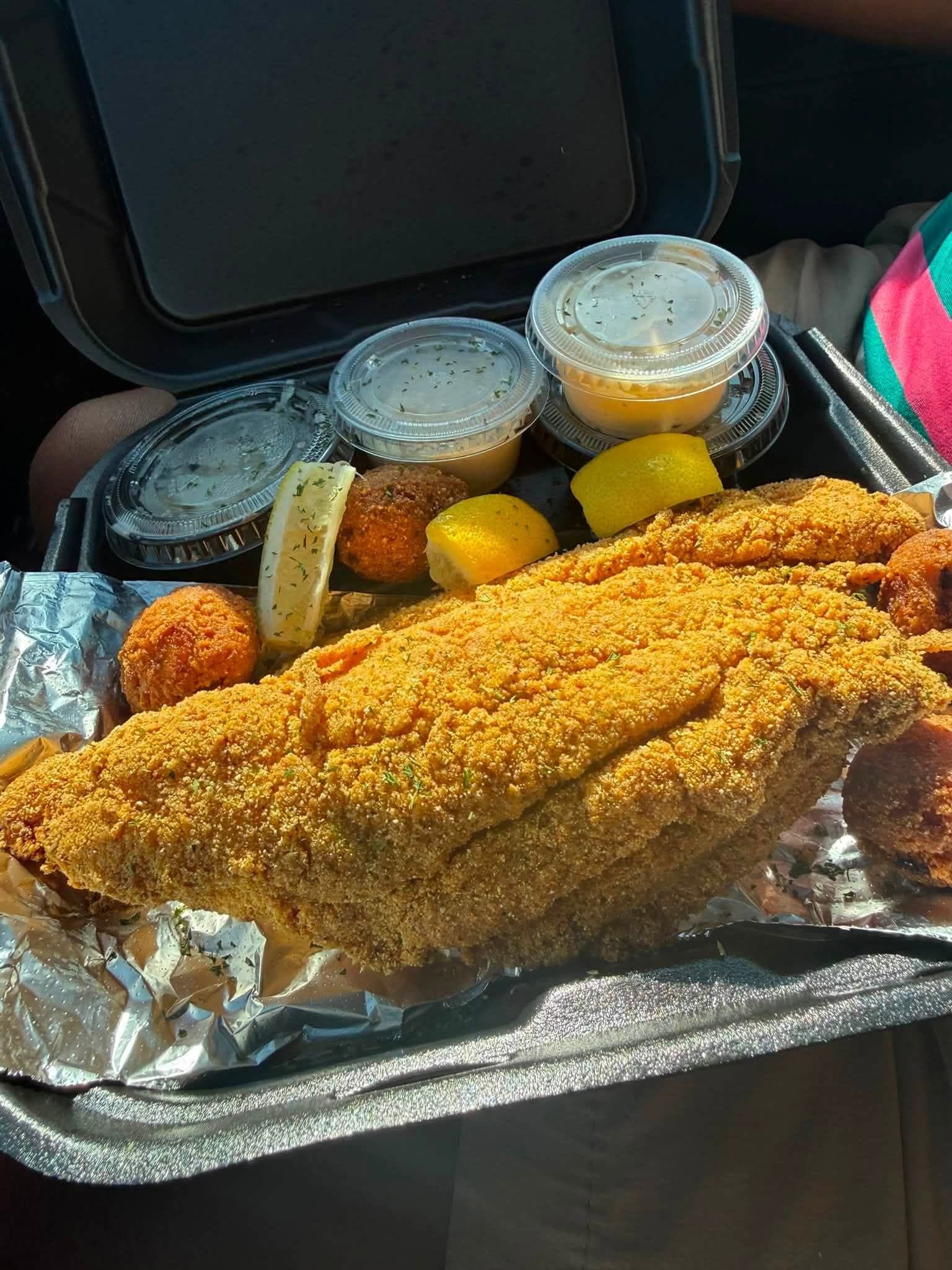 Whole fried catfish fillet with pickles, corn, and coleslaw